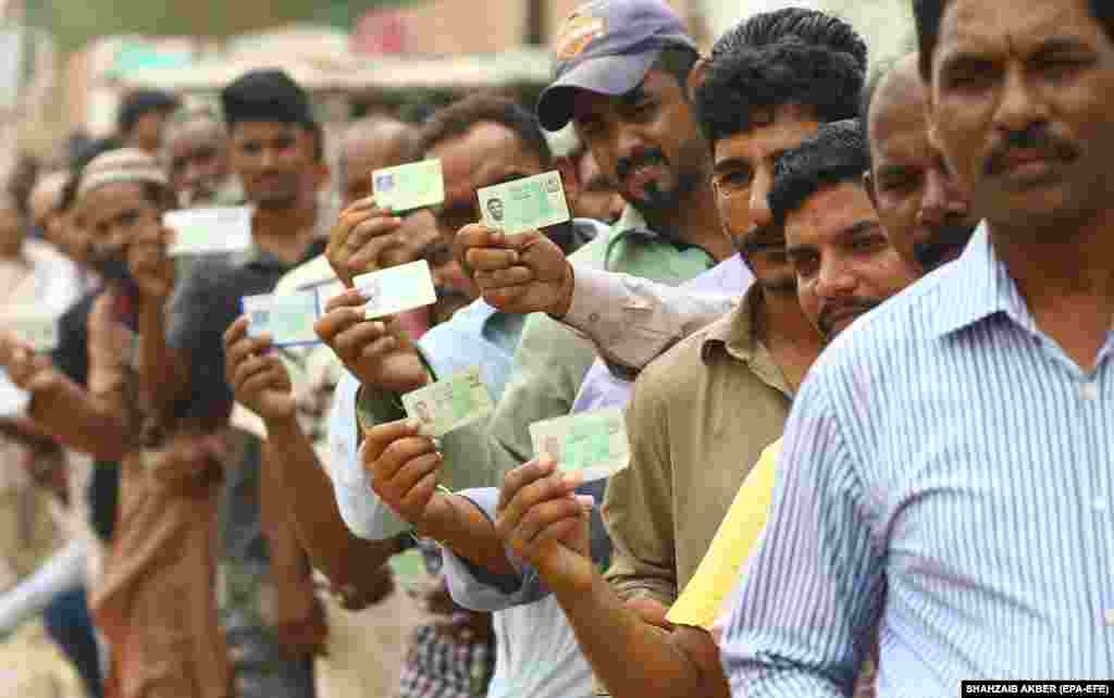 Voters show their national identity cards as they line up to cast their ballot during general elections in Karachi, Pakistan, on July 25. The elections were the second in Pakistan&#39;s history in which a government was able to complete its term to make way for another government, after being ruled by military dictators for half of the 71 years of its existence since its founding in 1947. (EPA-EFE/Shahzaib Akber)