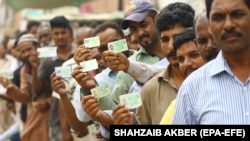Voters show their National Identity Cards as they line up to cast their ballot during general elections in Karachi on July 25