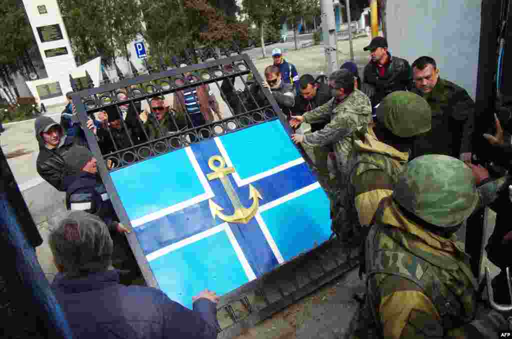 Ukraine -- People remove the gate of Ukrainian navy headquaters as Russian troops stand guard in Crimean city of Sevastopol on March 19, 2014