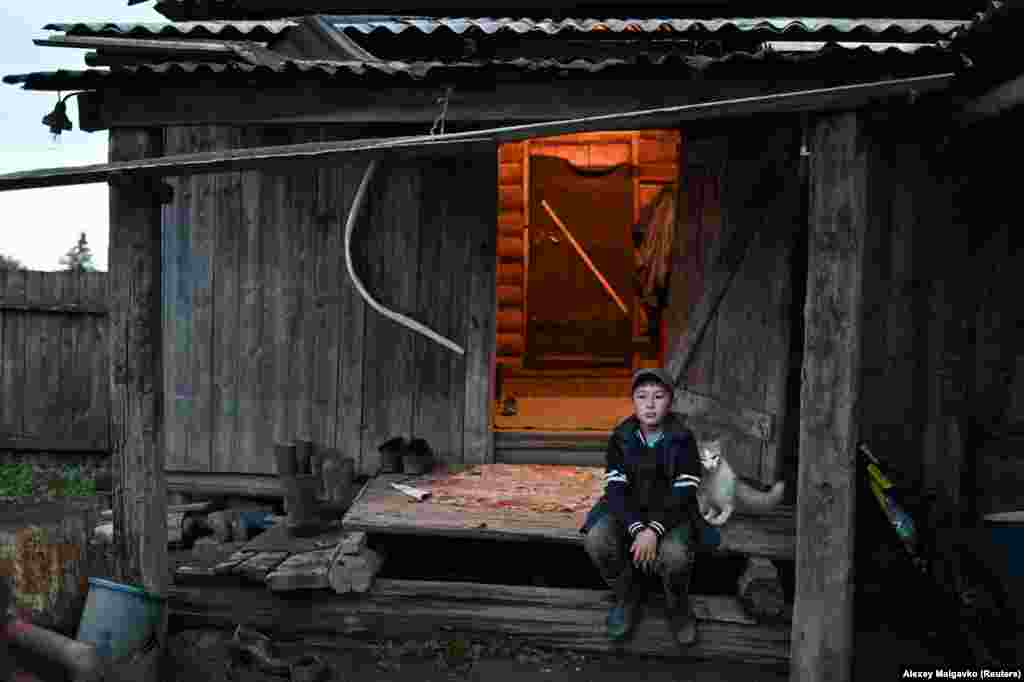 Ravil Izhmukhametov sits outside his family house. The boy says he has no interest in moving to a big city, but knows that soon he &quot;will have no choice.&quot;