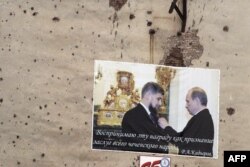 Плакат, на котором изображен президент России Владимир Путин, вручающий орден Рамзану Кадырову, на стене жилого дома в центре Грозного, 28 ноября 2005 года