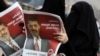 "Мұсылман бауырлар" қозғалысының кандидатын қолдаушы каирлік әйел Мохаммед Мурсидің үгіт-насихатын оқып тұр. 18 маусым 2012 жыл