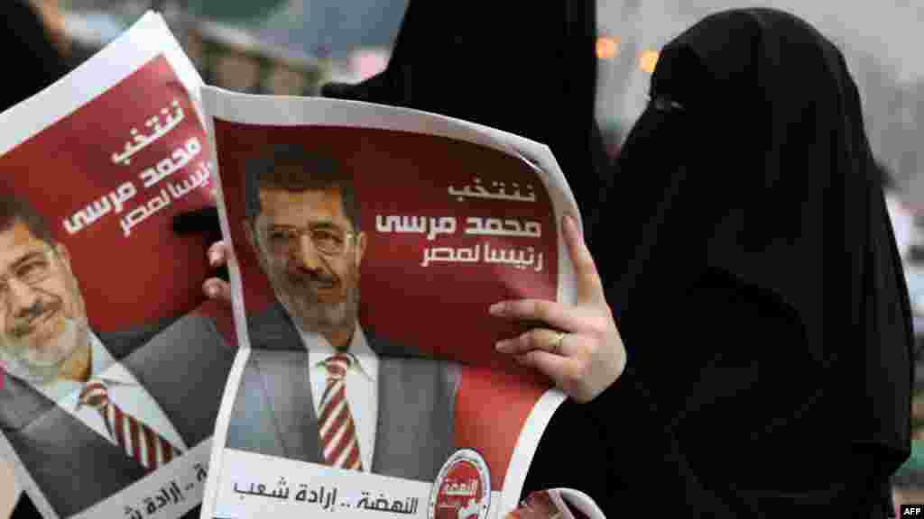 Female supporters of Muslim Brotherhood candidate Muhammad Morsi hold campaign fliers bearing his portrait during celebrations on Cairo&#39;s Tahrir Square on June 18. Islamist candidates claimed victory in Egypt&#39;s first free presidential vote since the 2011 Arab Spring uprising. (AFP/Patrick Baz)