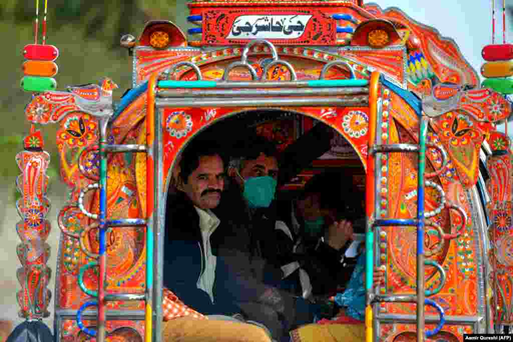 Residents wearing face masks as a preventive measure against the spread of the coronavirus sit in a passenger truck on a street in Rawalpindi, Pakistan. (AFP/Aamir Qureshi)