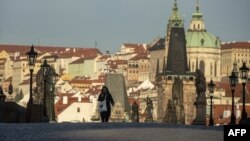 Жена со маска на Карлов Мост во Прага во март, кога исто така беше задолжително носењето маски
