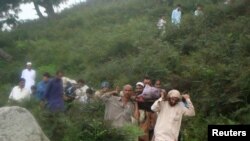 Volunteers walk down a mountain carrying the remains of victims after a helicopter crashed near Mansehra, in Pakistan's northwestern Khyber Pakhtunkhwa province on August 7.