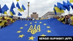 Një flamur i BE-së me emblemën kombëtare të Ukrainës shpaloset gjatë një tubimi në Sheshin e Pavarësisë në Kiev, Ukrainë. (Fotografi nga arkivi)