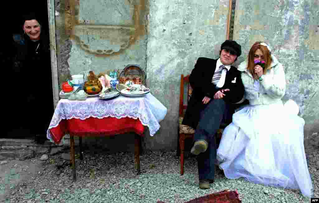 Two women wearing comic wedding suits pose for a photographer in a street market in Tbilisi, Georgia. (AFP/Vano Shlamov)