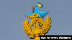 A worker takes a selfie as he stands with a Ukrainian flag on a Soviet-style star in Moscow on August 20.