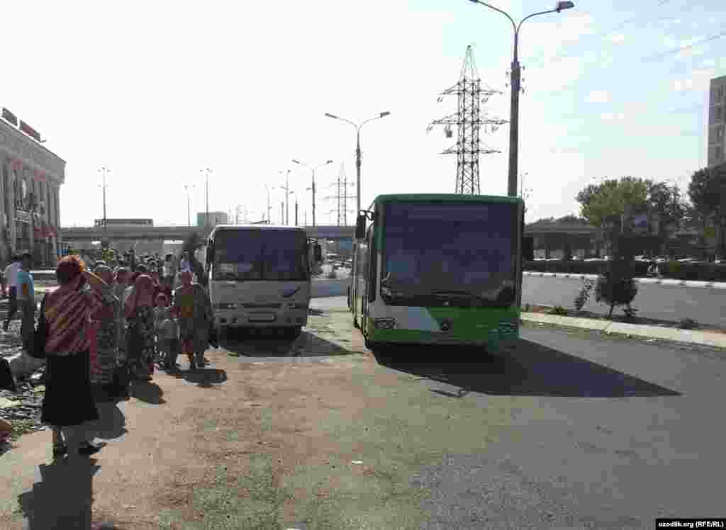 Travelers wait at a bus stop in Tashkent. With public buses rerouted to carry workers to the cotton fields, fewer are running their regular routes, meaning longer waits. 