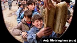 Një fëmijë refugjat shqiptar i Kosovës duke marrë bukë në qendër të Kukësit më 20 prill të vitit 1999