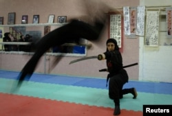 A female Ninjutsu practitioner jumps over a sword as members of various schools showcase their skills to the media in their gym, northwest of Tehran, in February 2012.