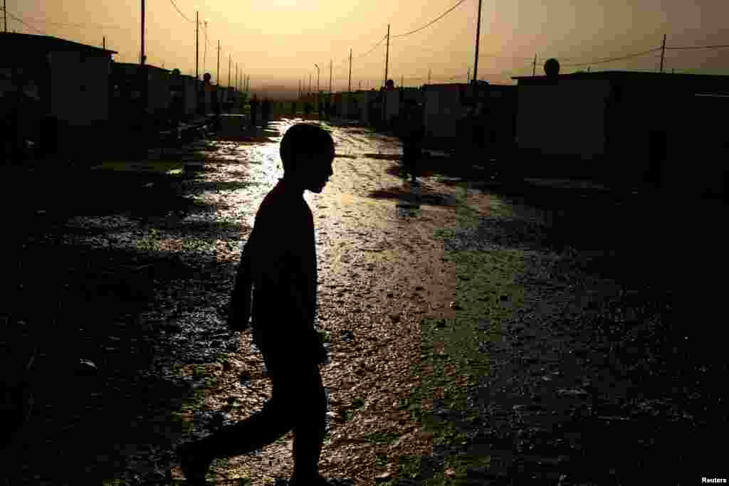 A displaced boy walks past wastewater at the Debaga refugee camp near Irbil in Iraq. (Reuters/Zohra Bensemra)