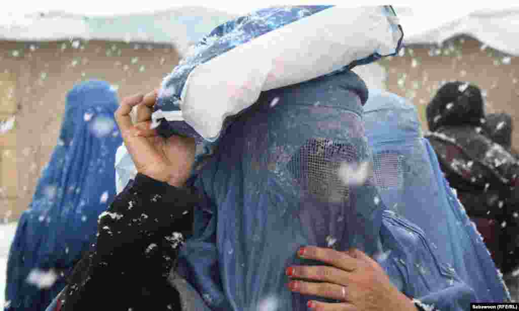 A woman carries a package she received at the aid distribution point.