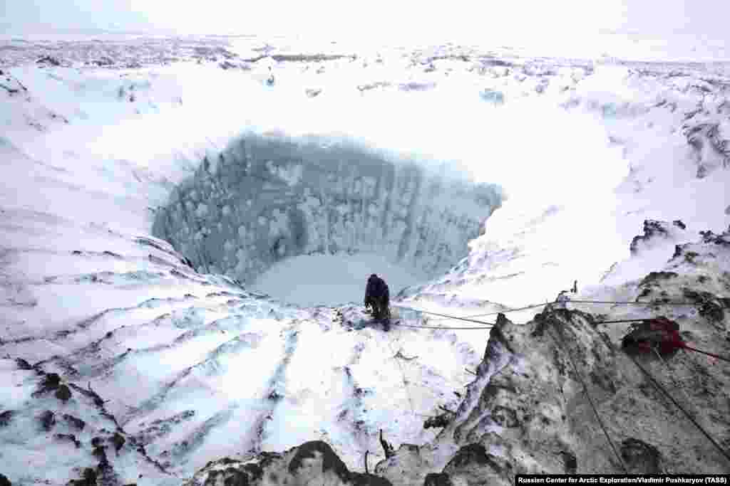 A scientist climbs to the bottom of a 200-meter-deep crater on Russia&#39;s Yamal Peninsula. (Vladimir Pushkarev/TASS)