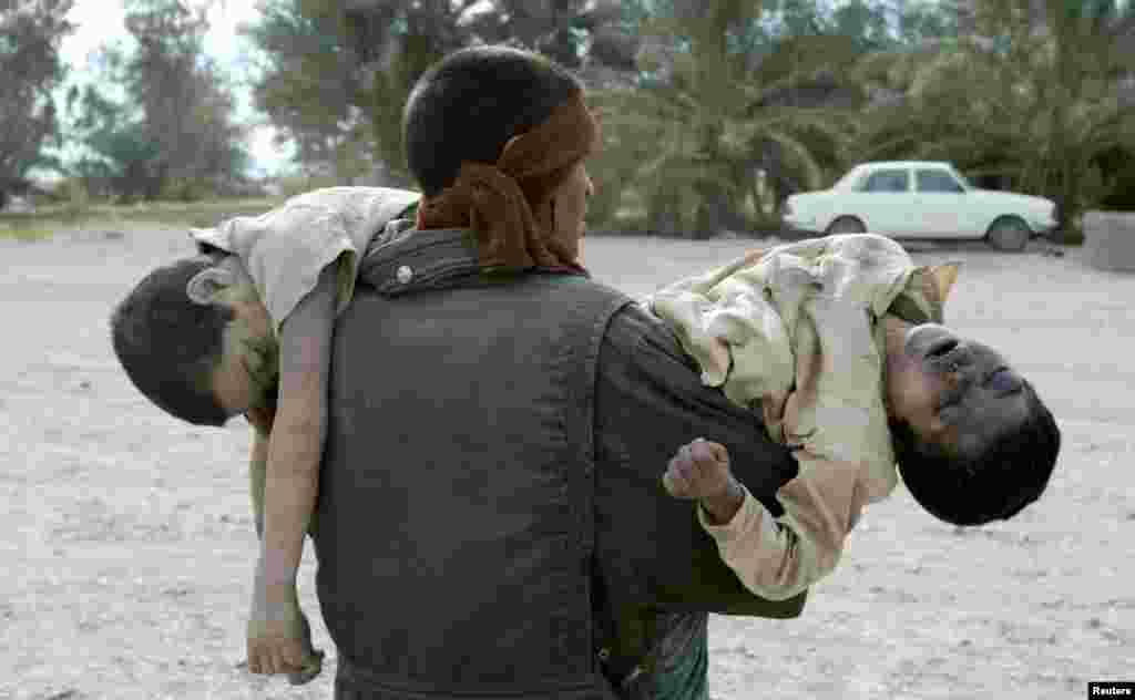 A man carries two brothers who were killed when their home collapsed during an earthquake in Bam December 27, 2003. International rescue workers hacked desperately through flattened debris for survivors and cemeteries overflowed in Iran's ancient Silk Road city of Bam after an earthquake that killed more than 20,000 people. REUTERS/Caren Firouz