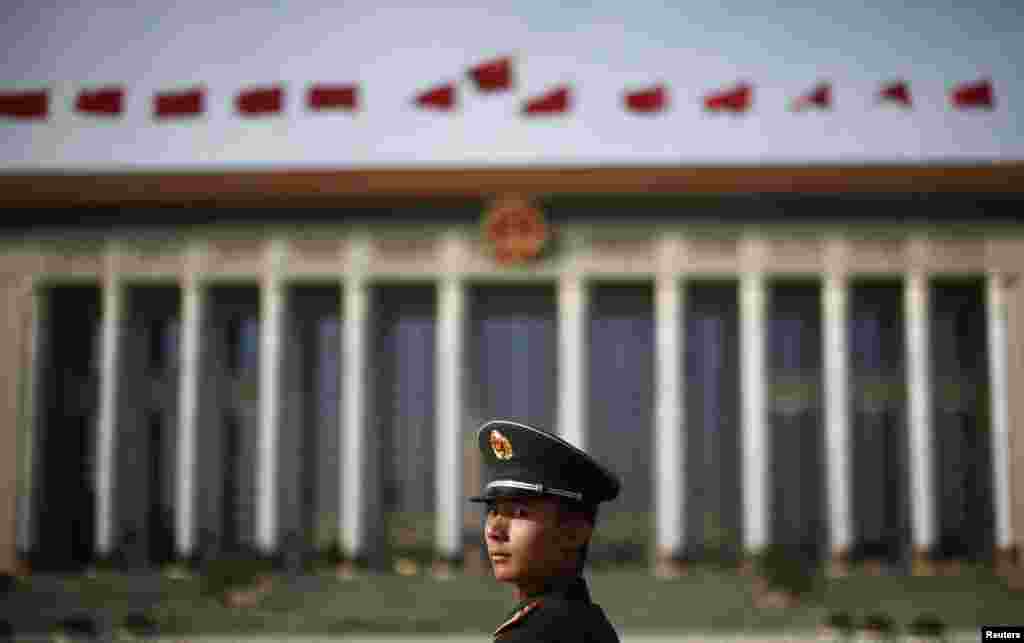 د بیجیګ په تانانمېن چوک کې د ولسي ستر تالار مخې ته د نیمه پوځي پولیس افسر ولاړ. A paramilitary police officer stands in front of the Great Hall of the People in Beijing&#39;s Tiananmen Square.