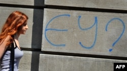 Женщина идет вдоль здания, на стене которого надпись: "ЕС?" Белград, июнь 2011 года.