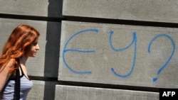 A woman in downtown Belgrade walks past graffiti that says "EU?"