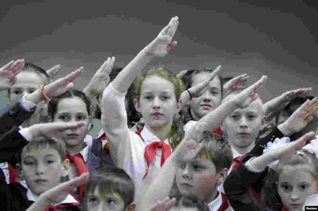 Russian children wearing red neckerchiefs, a symbol of the Pioneer Organization, salute while posing for a picture during a ceremony for the inauguration of 18 newly adopted members at a school in the Stavropol region. (Reuters/Eduard Korniyenko)