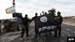 Iraqi soldiers pose with an Islamic State group flag as they hold a position in the village of Gogjali, a few hundred meters from Mosul's eastern edge on November 2.