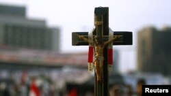 Egypt -- A Christian opposition supporter carries a cross amid the crowd on Tahrir Square in Cairo, 09Feb2011