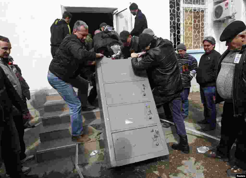 Ukraine -- Men carry a safe out of the naval headquarters after it was taken over by pro-Russian forces in Sevastopol, March 19, 2014