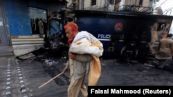 On November 28, a man walks past a police prison van destroyed during clashes between police and protesters a day after the Tehreek-e-Labaik Pakistan Islamist political party called off nationwide protests in Islamabad.