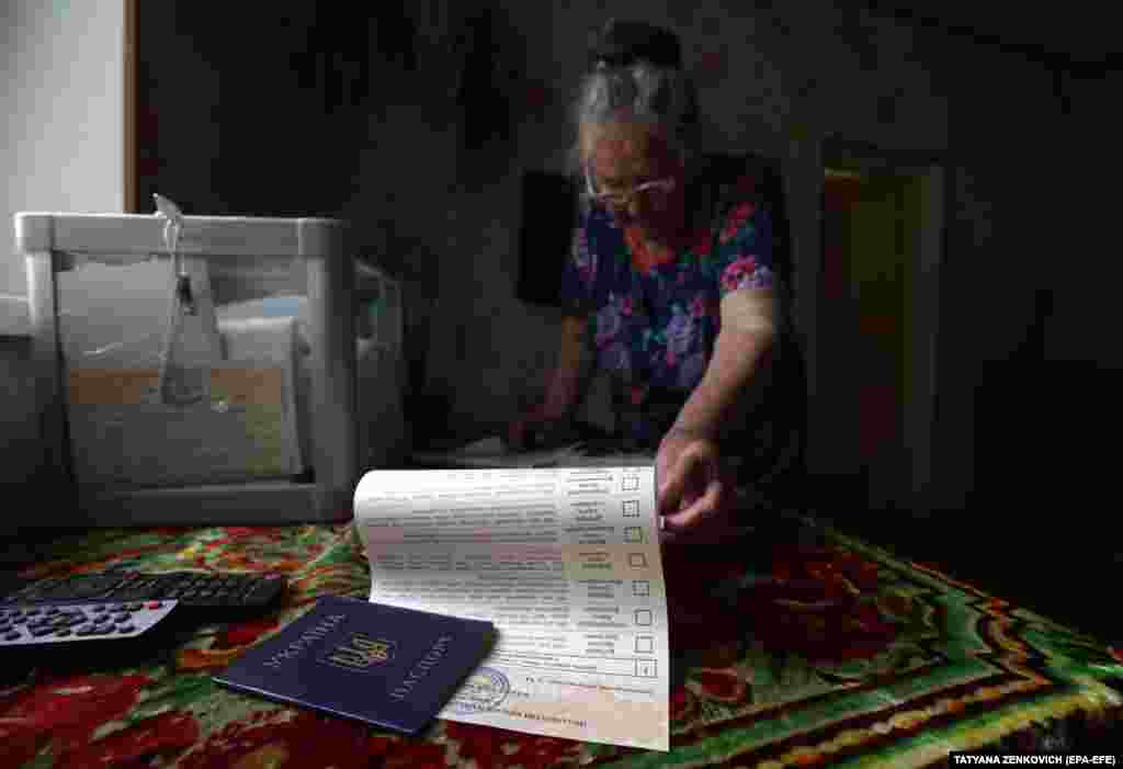 A woman reads her ballot paper before casting it into a mobile ballot box in the village of Velyki Dmytrovychi near Kyiv. (EPA-EFE/Tatyana Zenkovich)