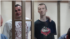 Ukrainian film director Oleh Sentsov (left) and Oleksandr Kolchenko sing the Ukrainian national anthem as they are sentenced by a Russian court on terrorism charges that have been condemned by many as fabricated. The two mean are among at least 12 Ukrainians who are being held in Russian prisons for convictions that have been denounced by Kyiv and Western governments. 