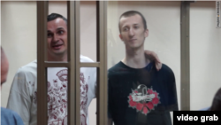 Ukrainian film director Oleh Sentsov (left) and Oleksandr Kolchenko sing the Ukrainian national anthem as they are sentenced by a Russian court on terrorism charges that have been condemned by many as fabricated. The two mean are among at least 12 Ukrainians who are being held in Russian prisons for convictions that have been denounced by Kyiv and Western governments. 