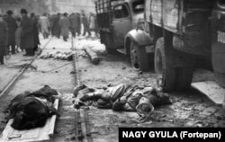 Покрытые пылью тела в форме в Будапеште в 1956 году. В ходе восстания советские войска были на четыре дня выведены из Будапешта. Восставшие открыли двери тюрем, чтобы выпустить политзаключенных, а также убили некоторых наиболее ненавистных сотрудников госбезопасности