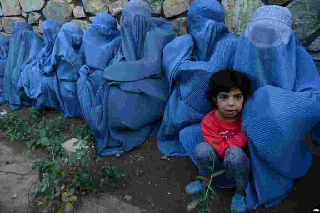 Afghan women wait with a child to get food from a distribution scheme held during Ramadan in Herat. (AFP/Aref Karimi)
