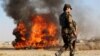 An Afghan soldier stands guard as authorities burn drugs seized during counternarcotics operations in the southern province of Helmand. 