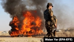 An Afghan soldier stands guard as authorities burn drugs seized during counternarcotics operations in the southern province of Helmand. 