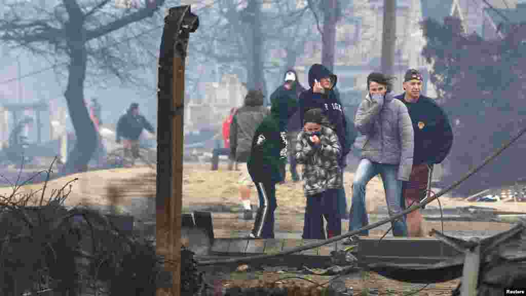 People stand among homes devastated by fire and the effects of Hurricane Sandy in the Breezy Point section of Queens, New York.