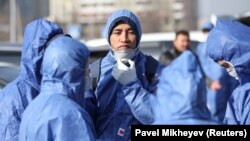 Сотрудники в защитных костюмах во время санобработки. Алматы, 27 марта 2020 года.