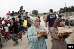 Беженки из лагеря Идомени несут дрова для отопления и разогрева пищи