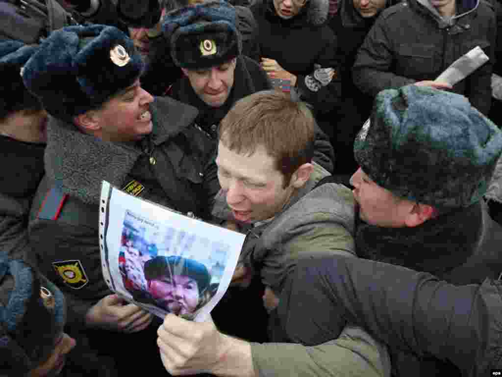 Police officers wrestle a protester holding a portrait of Moscow Mayor Yury Luzhkov.