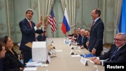 U.S. Secretary of State John Kerry (standing left) holds up a pair of Idaho potatoes as a gift for Russian Foreign Minister Sergei Lavrov (standing right) at the start of their meeting at the U.S. ambassador's residence in Paris on January 13.