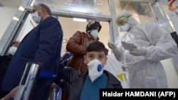 پرسنل بهداشتی در حال پخش برگه‌های اطلاعاتی بین مسافرانی که از ایران وارد نجف در عراق شده‌اند