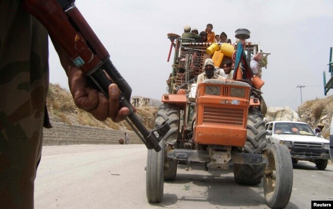 A soldier stands guard as a tractor carrying refugees fleeing the military offensive against militants in North Waziristan drives past a checkpoint in Bannu in 2014.