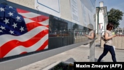 A woman walks by a board with consular information outside the U.S. Embassy in Moscow on August 22.