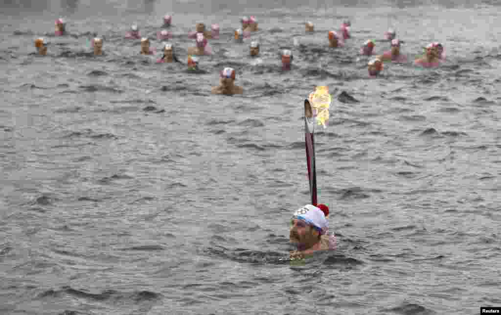 Члены красноярского спортивного клуба плывут с факелом зимней Олимпиады-2014 по реке Енисей. 26 ноября 2013 года.