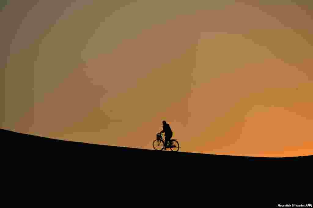 An Afghan man rides a bicycle up a a hill during sunset in Jalalabad. (AFP/Noorullah Naftoon)