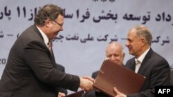 Patrick Pouyanne (left), chairman and CEO of the French energy company Total, shakes hands with Ezzatollah Akbari, managing director of the Petropars Group, after signing an offshore gas field agreement in Tehran on July 3.