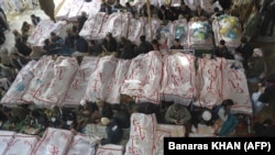 Pakistani Shi'ite Muslims gather around the coffins of the bombing victims as they demonstrate in Quetta on February 18.