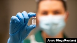 Медицинска сестра држи шишенце со вакцина против ковид-19 на Фајзер/БиоНтек.