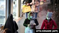 Iranian women wearing protective masks walk in a street in the capital Tehran on February 20,2020. 
