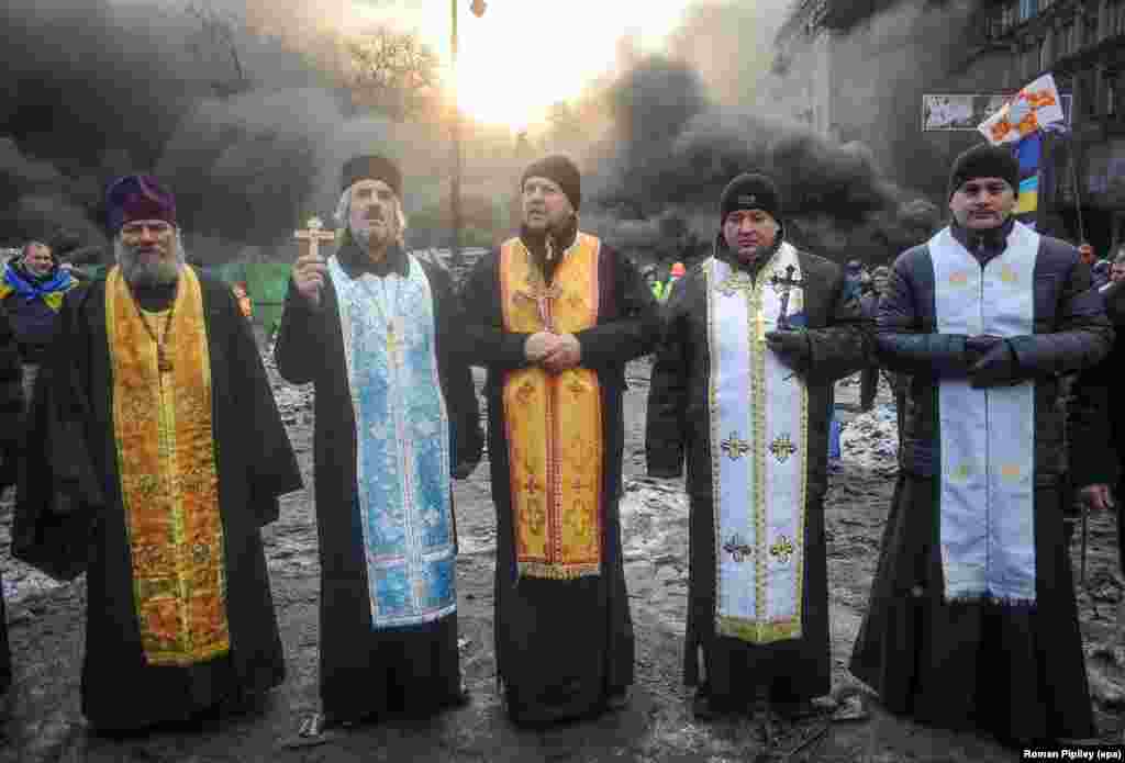 Priests say a prayer at the site of a standoff between protesters and police.